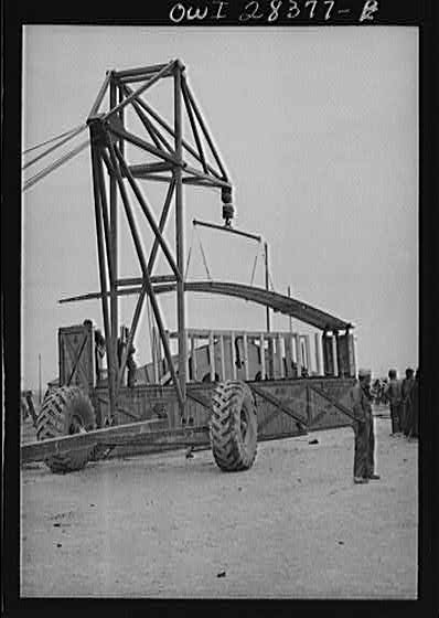A derrick moving a chassis as the men work ankle deep in water at an American truck assembly plant somewhere in Iran.