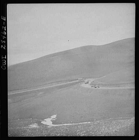 Somewhere in the Persian corridor. A United States Army truck convoy carrying supplies for Russia climbing a winding mountain road.