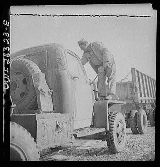 Somewhere in the Persian corridor. A United States truck convoy carrying supplies for the aid of Russia. The driver is cleaning the mud from his windshield.
