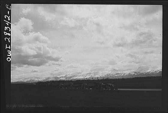 Somewhere in the Persian corridor. A United States Army truck convoy carrying supplies for Russia making a rest stop in a beautiful setting of clouds and snowcapped mountains.