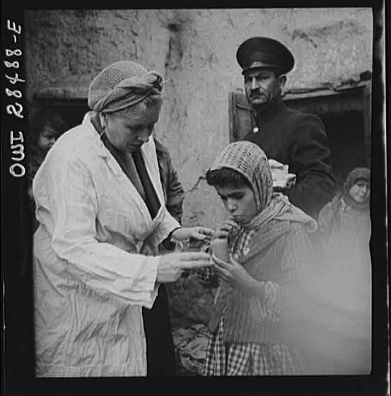 Teheran, Iran. Mrs. Louis Dreyfus, wife of the United States Minister to Iran, giving food to native children