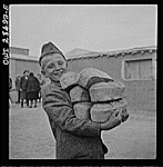 Teheran, Iran. Polish youngster carrying an armload of loaves of bread made from Red Cross flour at an evacuation camp