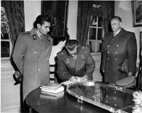 The Shah of Iran (left) looks on while an unidentified man signs the guestbook at George Washington's home, Mount Vernon.  - November 18, 1949.